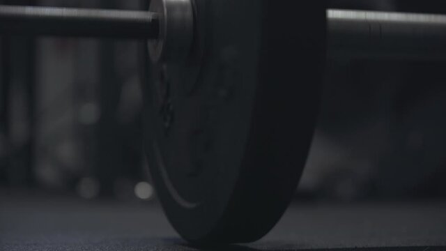 Close-up of barbell falling down on the floor in dark gym. Unknown sportsman throwing weights. Bodybuilding, endurance, training, exercising, lifestyle.