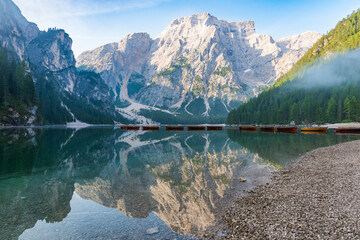 Early morning on the Lake Braies in Dolomites with a light fog over small wooden boats