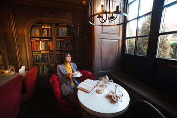 Beautiful dreamy girl in stylish sharp glasses. With a cup in his hands.