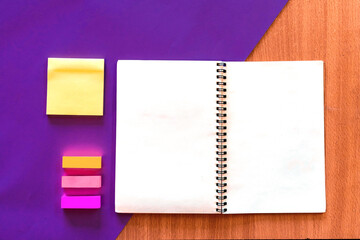 Education and business concept. Workplace with an open empty notebook, stickers, pen on a purple and wooden background
