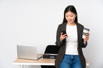 Business asian woman in her workplace isolated on white background holding coffee to take away and a mobile