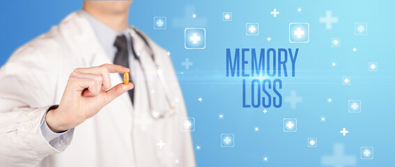 Close-up of a doctor giving a pill with MEMORY LOSS inscription, medical concept