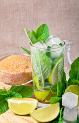 Cocktail mojito with mint leaves, lime and ice on a textile background.