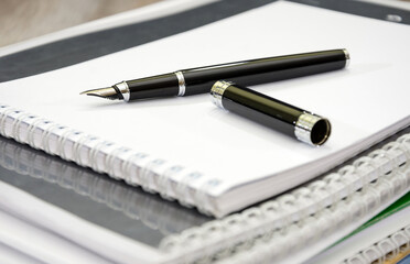 Pen on a stack of business paper / white notebooks / business documents