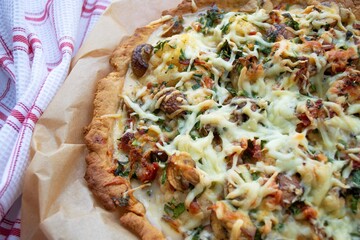 Composition in the rays of the daylight. Homemade quiche loren with a crispy crust (focus in the center on the crust) on craft paper, and a checkered towel nearby
