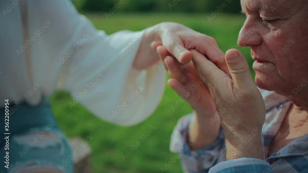 Wall mural close up of senior man holding and kissing woman hand on date in park