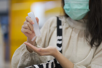 Asian girl with surgical mask using alcohol gel for cleaning hand