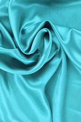 Luxury green fabric textured close up background.Smooth elegant silk or satin cloth texture.Wavy glossy cloth drapery.