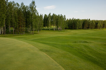 The photo shows a golf course, green grass and trees.