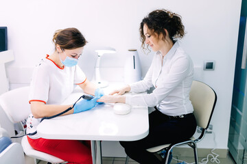 woman in a nail salon receiving a manicure by a beautician. trim