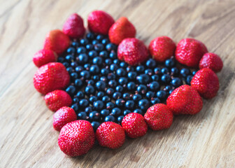Heart from berries, fresh berries on the wooden background, summer food