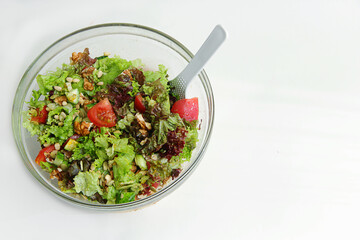 fresh vegetable salad in a glass plate on the side on a white background and there is a revenge for the inscription and advertising