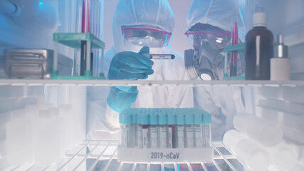 Laboratory workers examining covid-19 blood sample from fridge