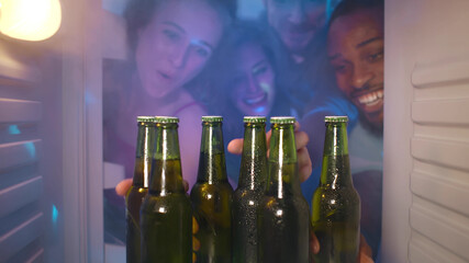 Group of young multiethnic friends sharing beer from fridge for home party