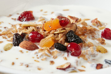 Granola (myusli) for breakfast with oatmeal, various seeds and dried fruits in a plate with milk close-up. Healthy and delicious diet breakfast.