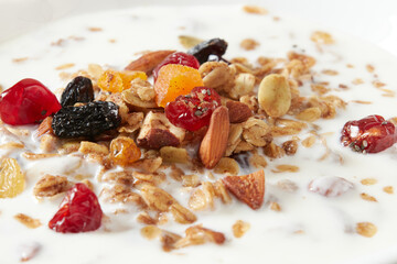 Granola (myusli) for breakfast with oatmeal, various seeds and dried fruits in a plate with milk close-up. Healthy and delicious diet breakfast.