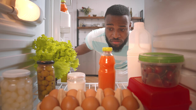 African Guy In Earphones Opening Fridge To Take Drink