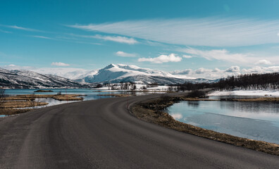 Road crossing beautiful nature reserve. Amazing snowy mountains landscape on Senja island, northern...