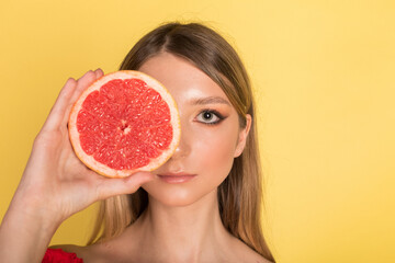 Beautiful young caucasian beauty girl portrait on yellow background with grapefruit