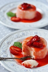 semolina Pudding in a beautiful plate with strawberry syrup and a strawberry . A piece of pudding is broken by a spoon. Soft focus.  