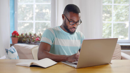 African american businessman using laptop at modern home office.