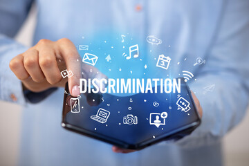 Businessman holding a foldable smartphone with DISCRIMINATION inscription, social media concept
