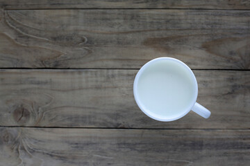 White mug with milk on a wooden background. The view from the top.