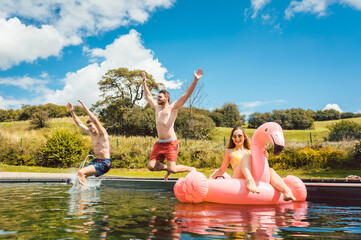 Friends jumping into the water of public pool
