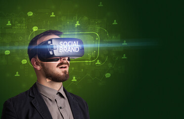 Businessman looking through Virtual Reality glasses with SOCIAL BRAND inscription, social networking concept