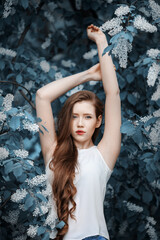 Portrait of woman on a background of blooming bird cherry.