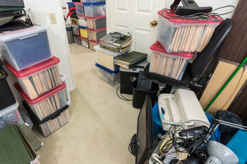 Office storage area with boxes, files, old equipment, mess and clutter.