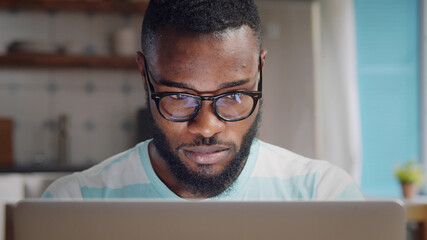 Afro-american young businessman using laptop at home.