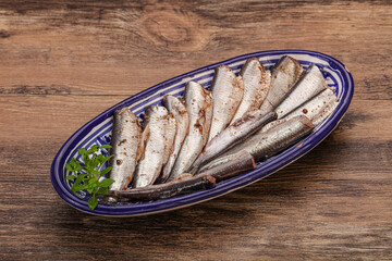 Anchovies in the bowl served basil leaves