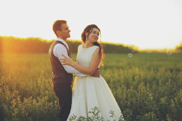 Happy bride and groom hug each other in the park at sunset. Wedding. Happy love concept.