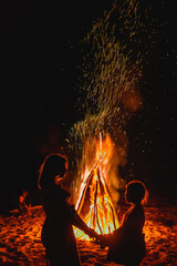 Silhouette of two girls on the background of a big bonfire in a summer scout camp.