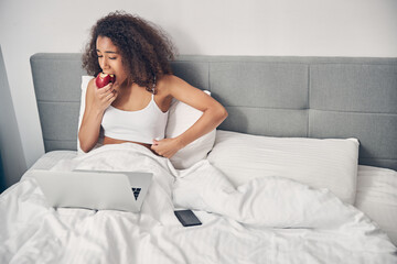 Dark-haired lady in a top sitting in bed