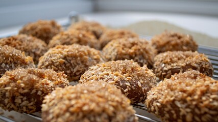 Artistic composition in natural sunlight. Homemade cookies with coconut on a metal grid, on a light background. Focus on the central biscuit, around the focus is specially blurred