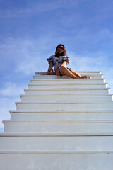 girl sit on top of white stairs to the sky, success concept 