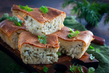 Jellied pie with cheese and herbs on a wooden board, selective focus