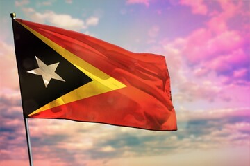 Fluttering Timor-Leste flag on colorful cloudy sky background. Prosperity concept.