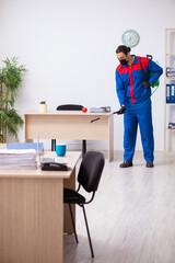 Young male contractor disinfecting office