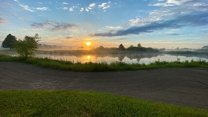 Fototapeta premium sunrise over golf course green and sand traps pond tree reflections