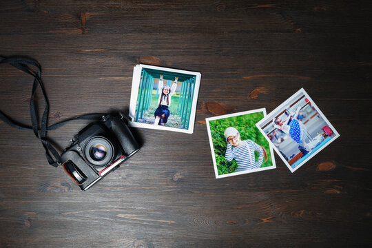 Photos and vintage camera on wood table background. Flat lay.