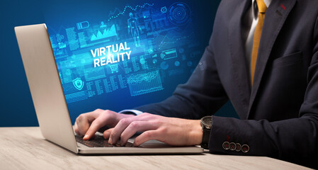 Businessman working on laptop with VIRTUAL REALITY inscription, cyber technology concept