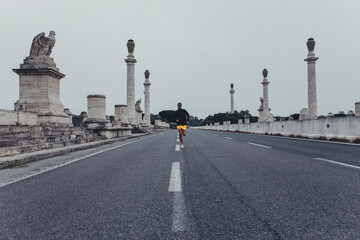Ragazzo sportivo si allena in solitudine correndo nel bel mezzo di una strada deserta di città