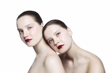 Portrait of two young beautiful girls with clean eye makeup and dark red lipstick