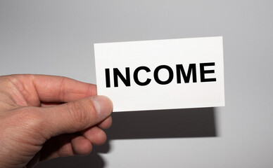 Message on the card INCOME, in hands of businessman.