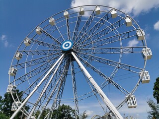 An empty Ferris wheel in an amusement Park, a bright blue summer sky. The attraction is closed due to the coronavirus pandemic, quarantine. Summer day, blue sky and white clouds. Video 4K