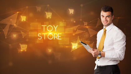 Businessman with shopping cart icons and TOY STORE inscription, online shopping concept