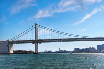 Double-layered suspension Rainbow Bridge in Tokyo Bay with the gantry cranes of the International Container Terminal of the Port of Tokyo in background.